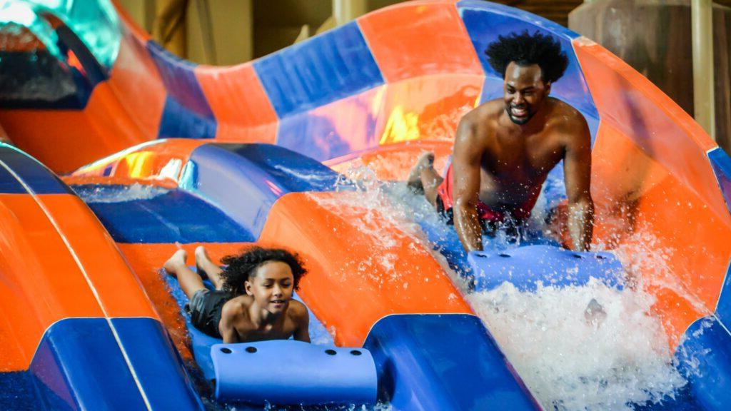 father and son slide down water slides